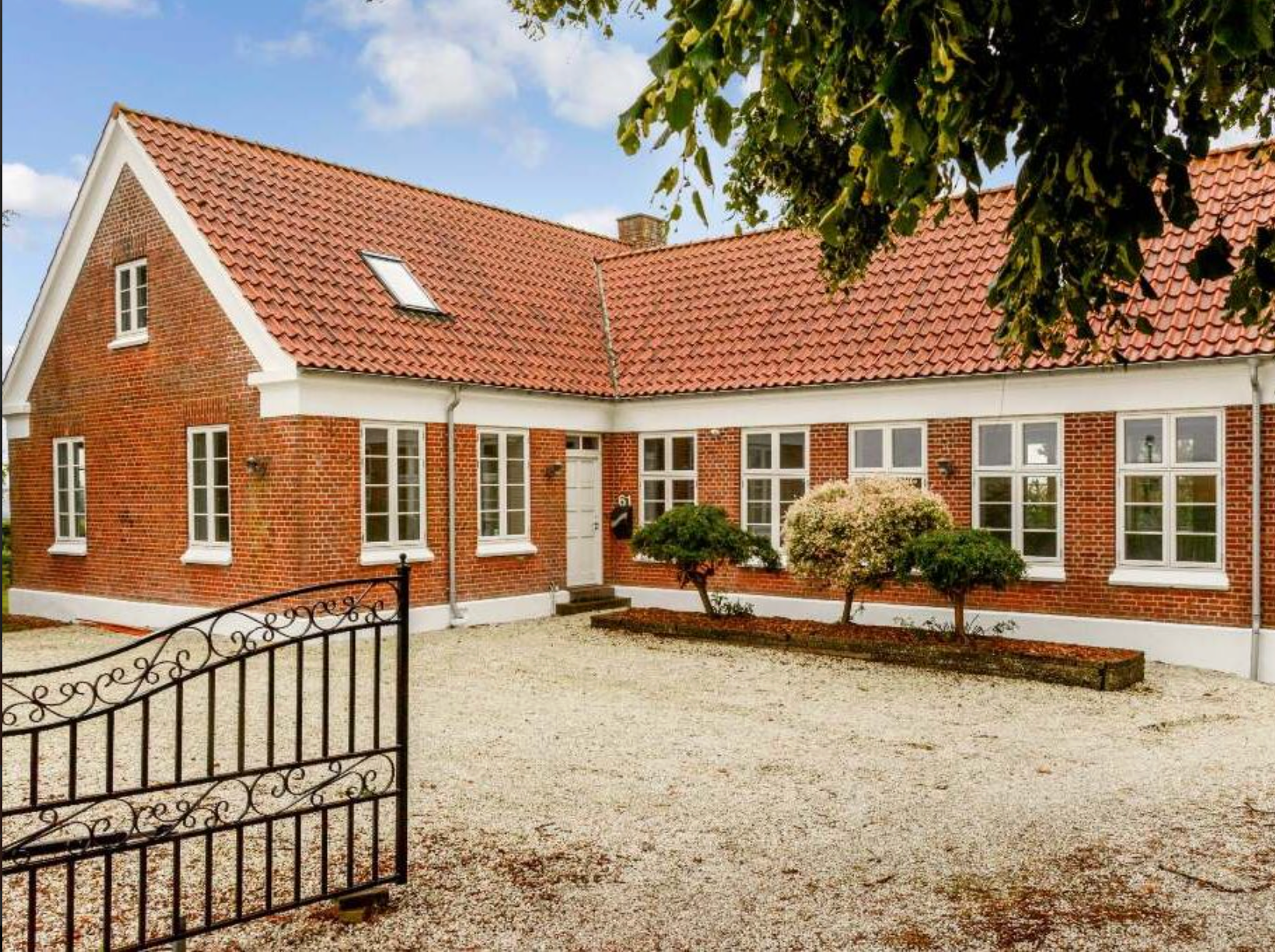 Huset Stjernestøvs rødstenshus set fra indkørslen med den sorte port